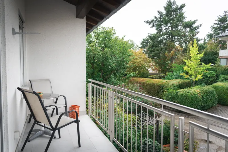 Balkon mit zwei Stühlen und Blick in einen grünen Garten
