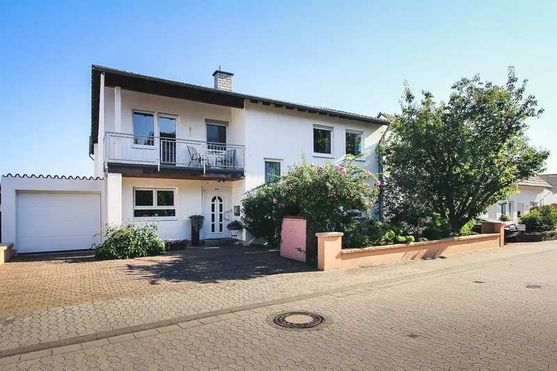 Das Haus in der Weinbergstraße mit Balkon im Obergeschoss und blühendem Vorgarten