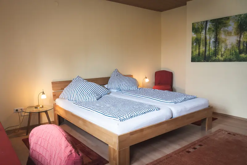 Zweites Schlafzimmer mit Doppelbett aus Holz und Waldbild an der Wand