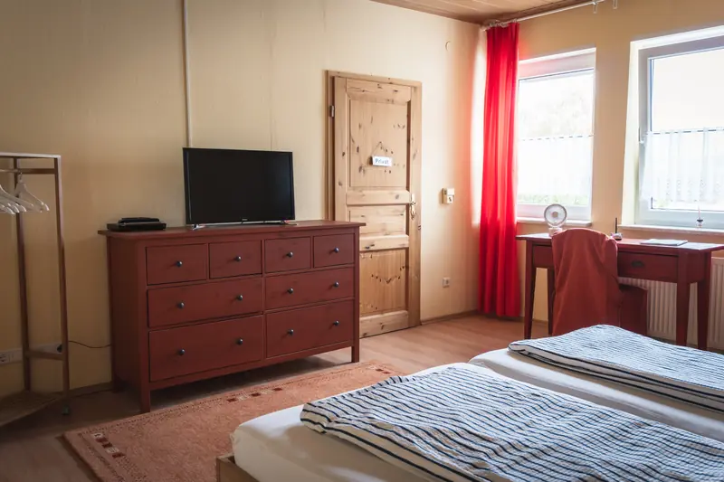 Zweites Schlafzimmer mit Doppelbett aus Holz, Kommode, TV und Schreibtisch