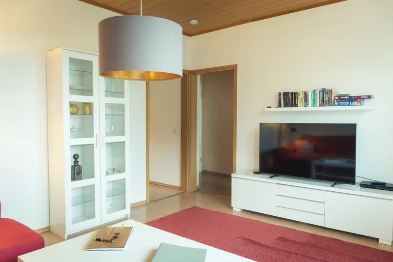 Wohnzimmer mit Vitrine, Flachbild-TV, Bücherregal und Gesellschaftsspielen
